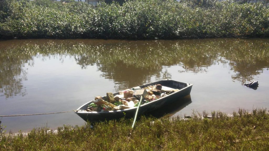 Barco usado na limpeza do rio Tavares com lixo dentro