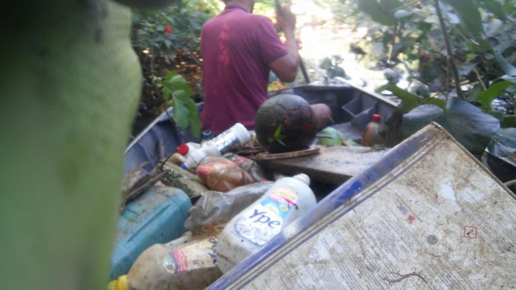 Moradores ao lado do lixo no barco usado na limpeza do rio Tavares